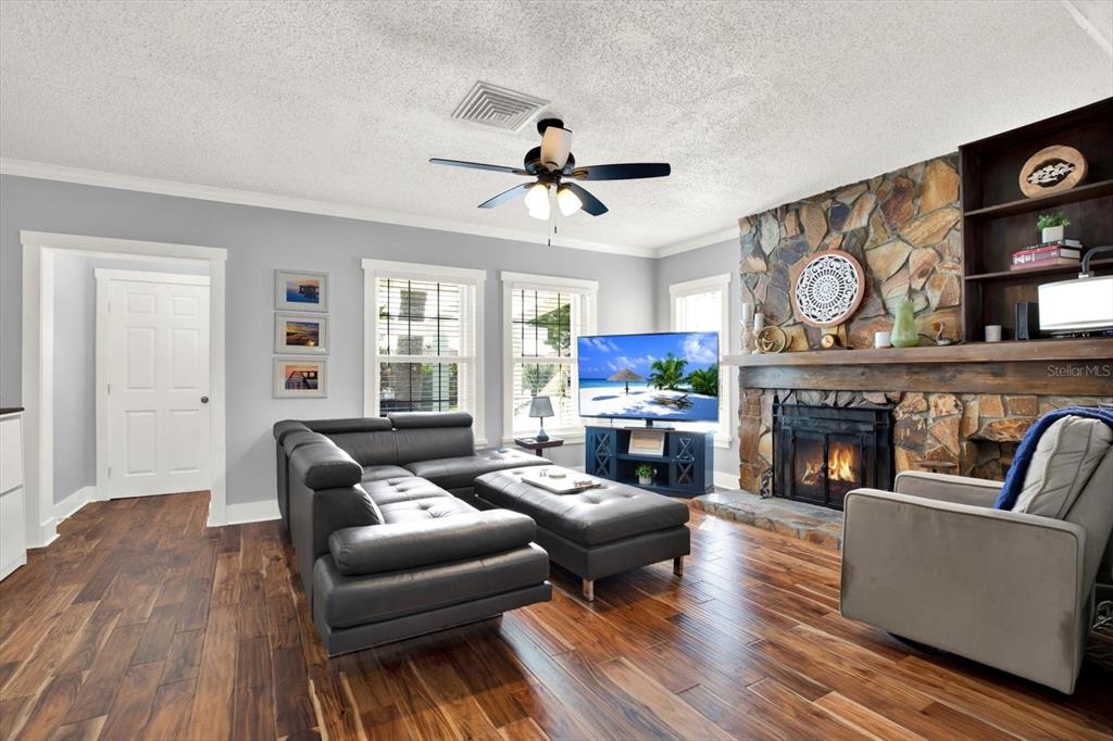 A living room features a stone fireplace, gray sectional sofa, and wood-look flooring — 15656 1ST STREET E, REDINGTON BEACH, FL