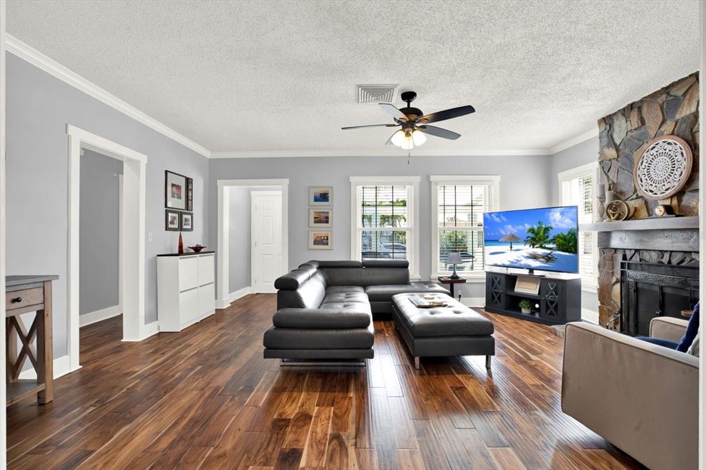 A living room features a dark leather sectional, hardwood floors, and a stone fireplace — 15656 1ST STREET E, REDINGTON BEACH, FL