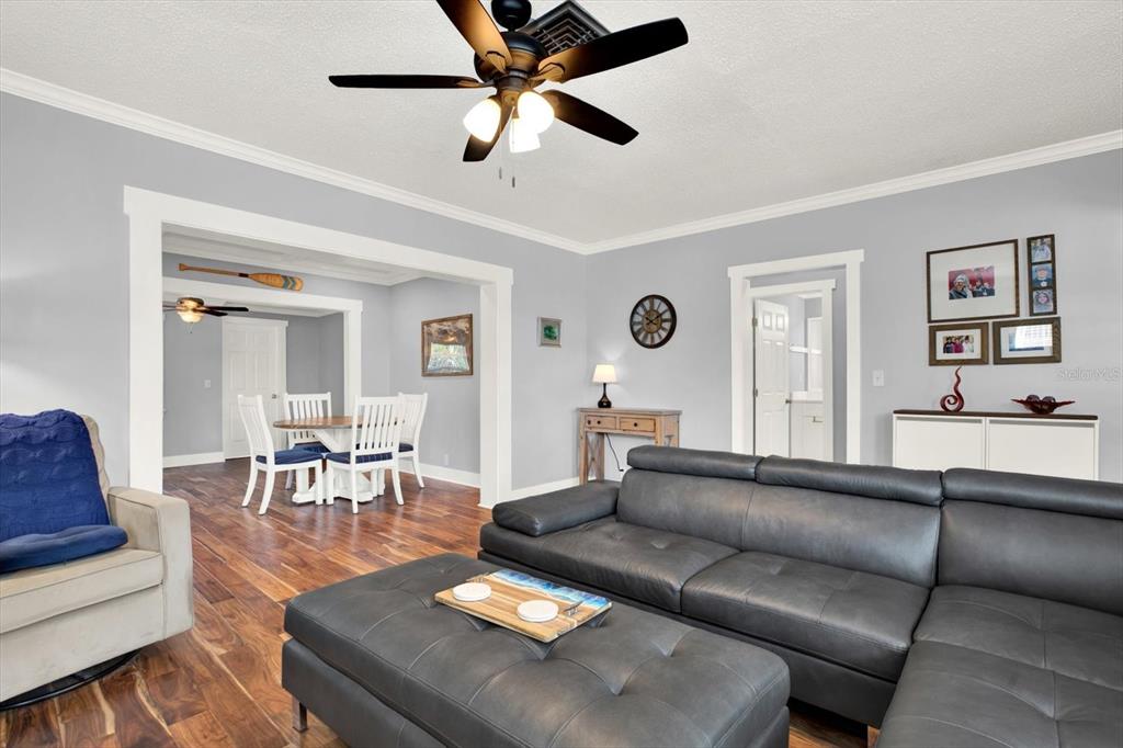 A living room with a grey sectional sofa, wood flooring, and an adjacent dining area — 15656 1ST STREET E, REDINGTON BEACH, FL