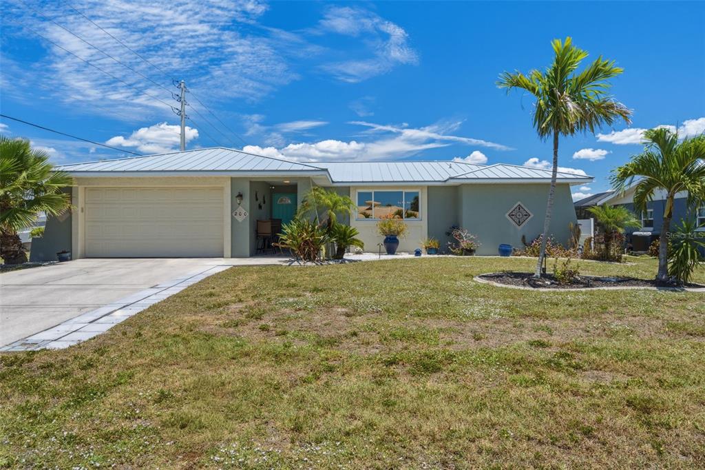 A single-story house with a light green exterior, metal roof, and a two-car garage — 200 BELAIRE COURT, PUNTA GORDA, FL