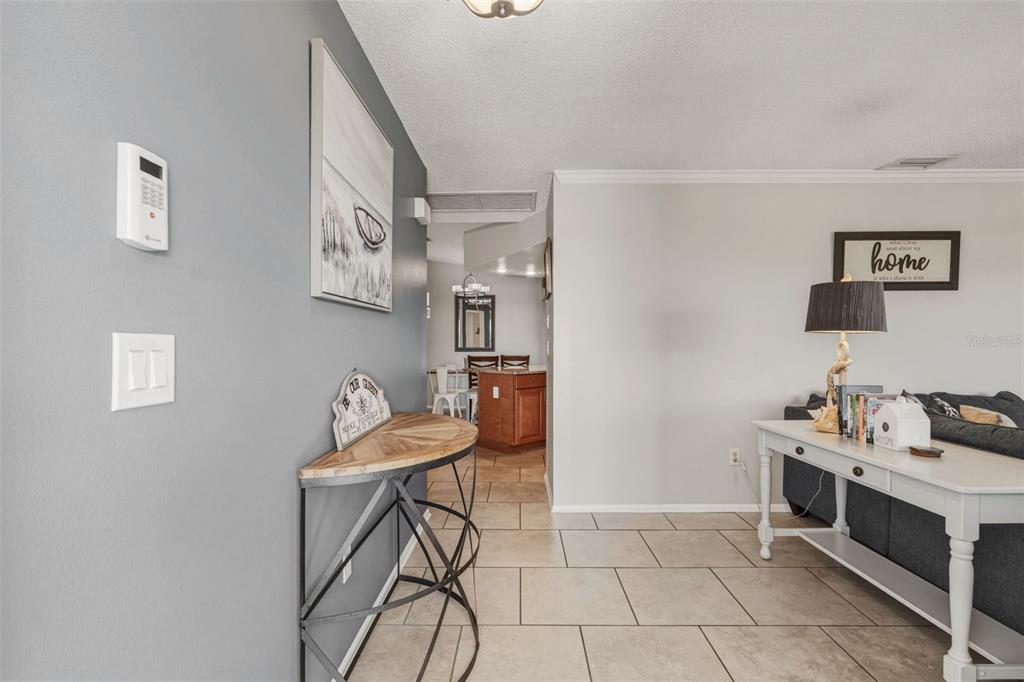 A living room with tile flooring, a gray accent wall, and a white console table — 200 BELAIRE COURT, PUNTA GORDA, FL