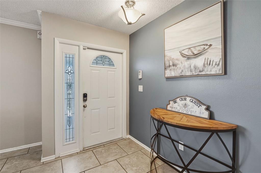 An entryway features a white front door, a blue accent wall, and a console table — 200 BELAIRE COURT, PUNTA GORDA, FL