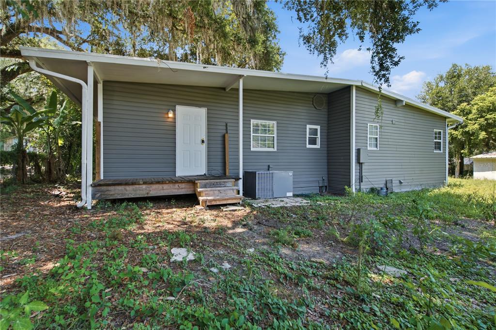 The exterior of a gray-sided house features a wooden deck, a white door, and windows — 39217 FIBELKORN ROAD, ZEPHYRHILLS, FL