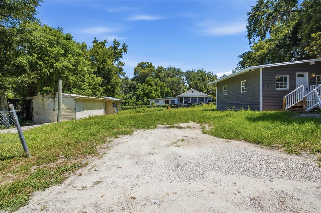 A gravel driveway leads toward a small detached garage and a house with gray siding — 39217 FIBELKORN ROAD, ZEPHYRHILLS, FL
