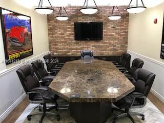 A conference room features a large stone table, black leather chairs, and a brick accent wall — 13499 Biscayne Blvd, North Miami FL 33181, NORTH MIAMI, FL