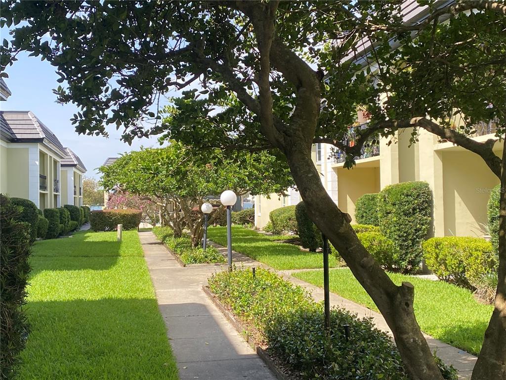 A paved walkway leads between apartment buildings with manicured lawns and mature trees — 1500 GAY ROAD UNIT 4D, WINTER PARK, FL