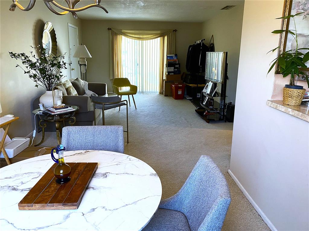 A living room and dining area feature a marble-topped table, carpeted floors, and sliding doors — 1500 GAY ROAD UNIT 4D, WINTER PARK, FL