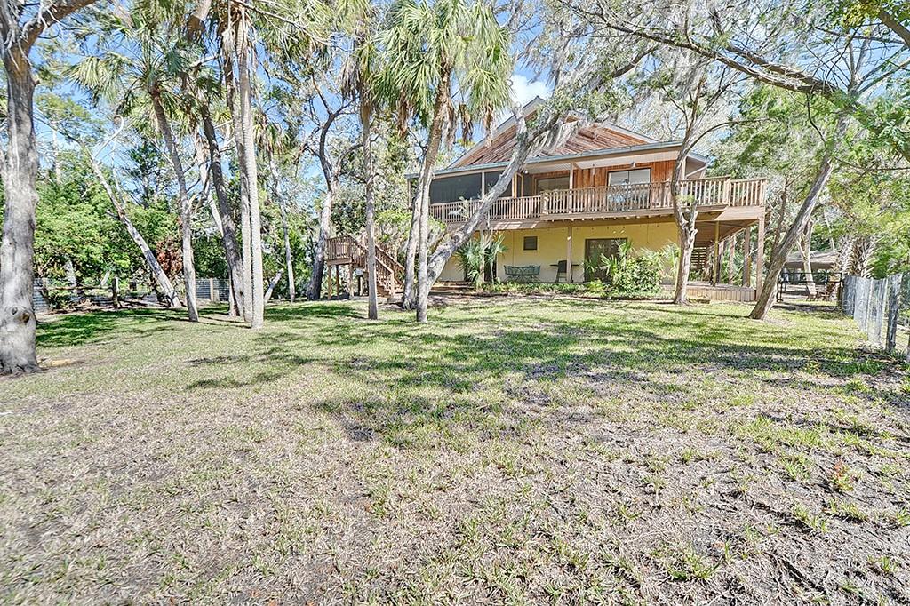 A two-story house with a wooden deck stands in a large, tree-filled grassy yard — 6618 S BEAGLE DRIVE, HOMOSASSA, FL
