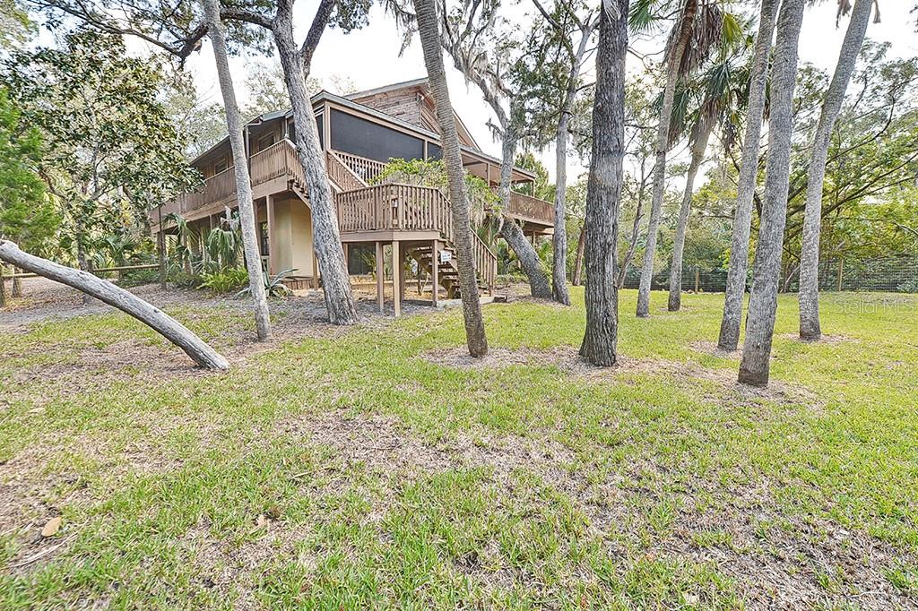 A two-story wooden house with a screened-in porch sits among trees in a grassy yard — 6618 S BEAGLE DRIVE, HOMOSASSA, FL