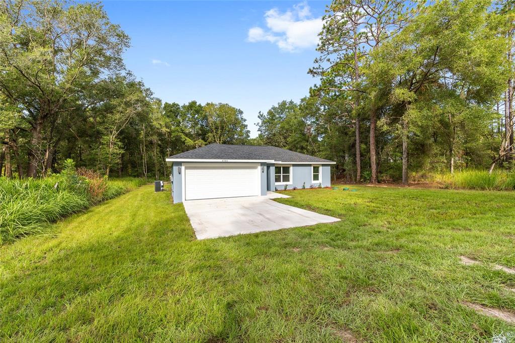 A single-story house with a light blue exterior, white garage door, and a concrete driveway — 2110 SW 159TH COURT, OCALA, FL