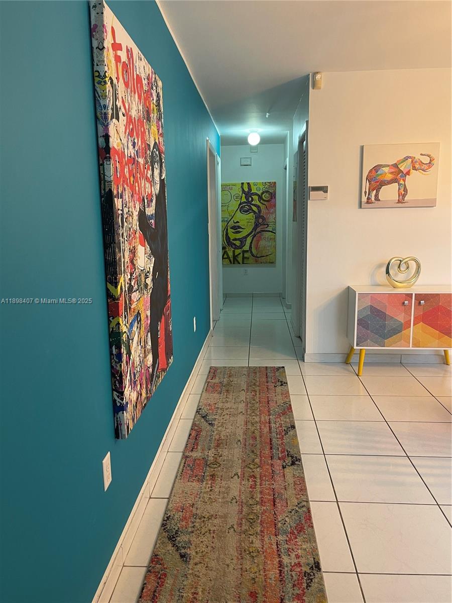 A hallway with white tile floors, a colorful runner rug, and vibrant wall art — 4521 NW 4th St # 4521, Miami FL 33126, MIAMI, FL