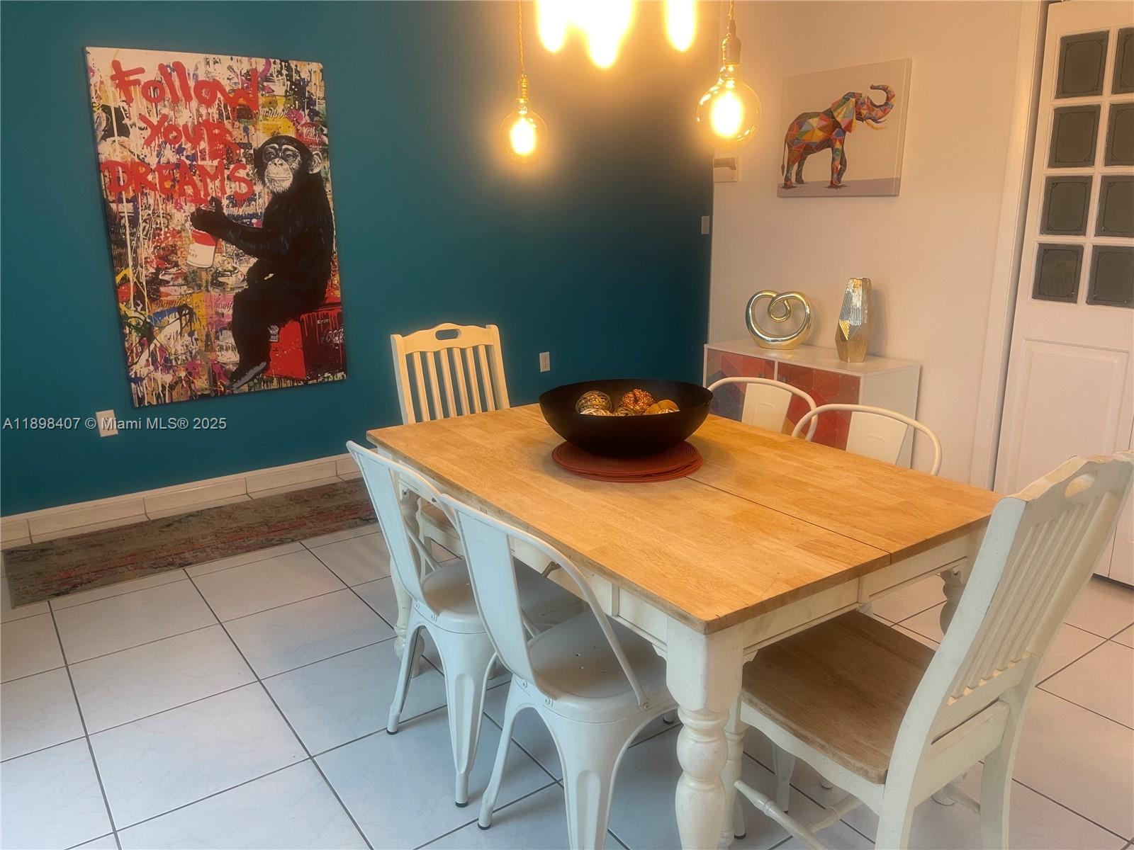 A dining room features a wooden table, white chairs, a teal accent wall, and artwork — 4521 NW 4th St # 4521, Miami FL 33126, MIAMI, FL