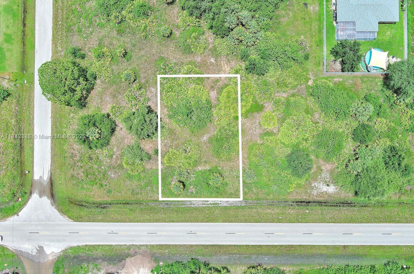 An aerial view shows a rectangular vacant lot outlined in white next to a paved road — 841 Milwaukee Blvd, Lehigh Acres FL 33974, LEHIGH ACRES, FL