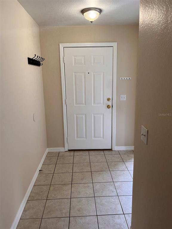 An entryway features beige walls, a white front door, and light-colored square floor tiles — 2005 N LAKE ELOISE DRIVE, WINTER HAVEN, FL
