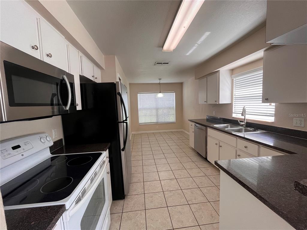 A kitchen with white cabinets, dark countertops, stainless steel appliances, and tile flooring — 2005 N LAKE ELOISE DRIVE, WINTER HAVEN, FL