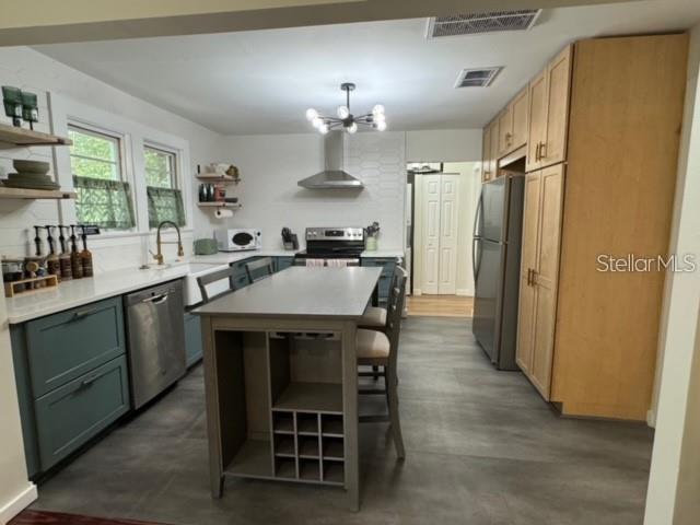 A kitchen features a central island, light wood cabinetry, blue lower cabinets, and stainless appliances — 1410 W HUMPHREY STREET, TAMPA, FL