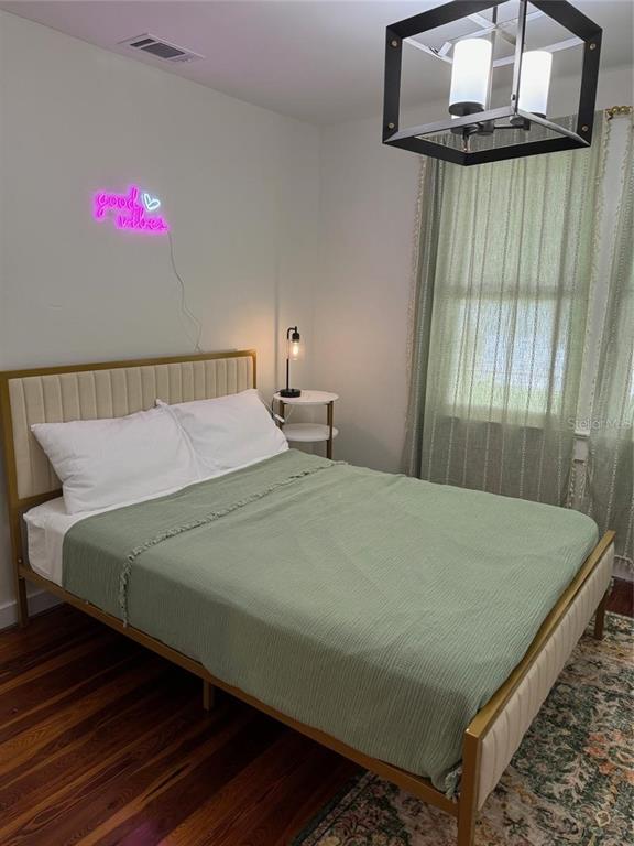 A bedroom features a bed with a green cover, a neon sign, and a chandelier — 1410 W HUMPHREY STREET, TAMPA, FL