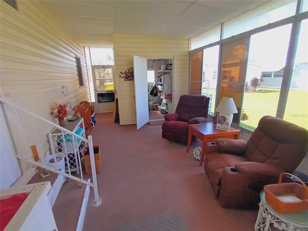 A sunroom with pink carpet, two recliners, and large windows overlooking a grassy yard — 5229 BEL AIR AVENUE, SARASOTA, FL