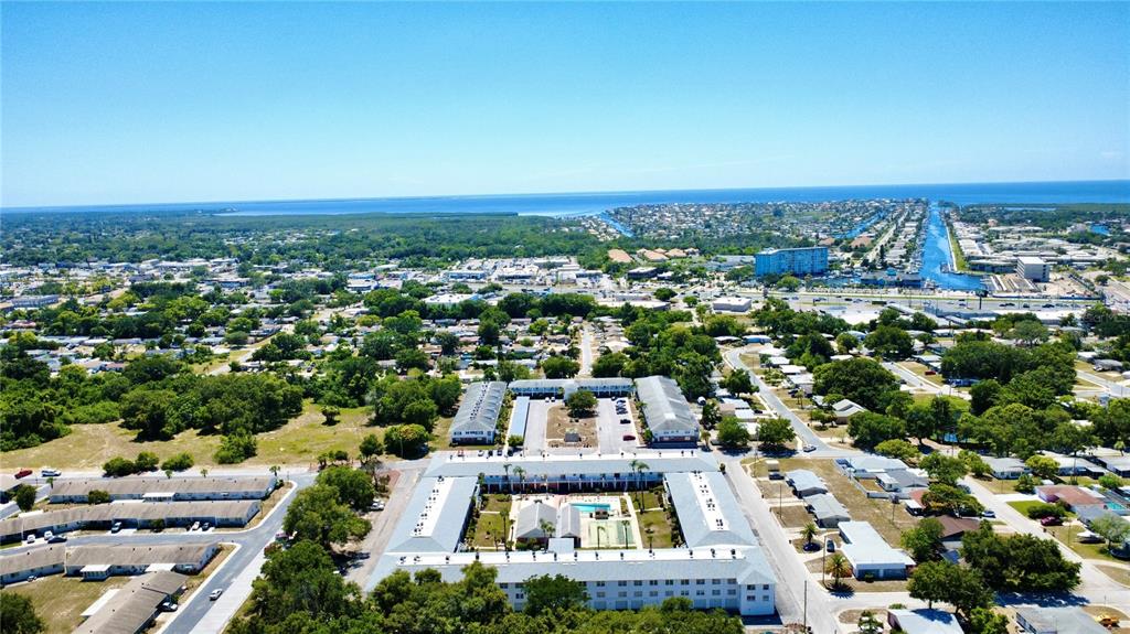 An aerial view shows a multi-story apartment complex with a central courtyard and swimming pool — 4747 AZALEA DRIVE UNIT 231, NEW PORT RICHEY, FL