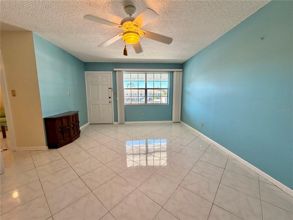 A living room features light blue walls, white tile flooring, and a ceiling fan — 4747 AZALEA DRIVE UNIT 231, NEW PORT RICHEY, FL