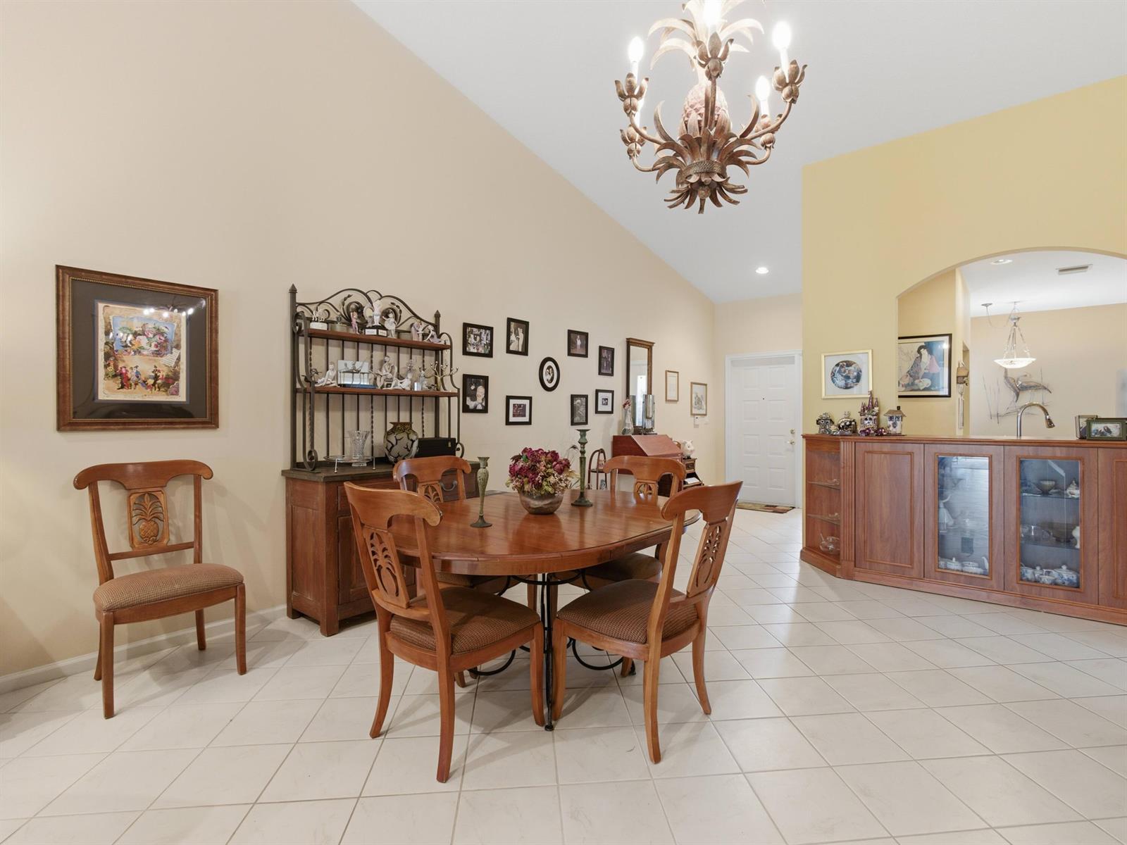 A dining room with a wooden table, chairs, hutch, and a chandelier under a vaulted ceiling — 9624 Crescent View Drive N, Boynton Beach FL 33437, BOYNTON BEACH, FL
