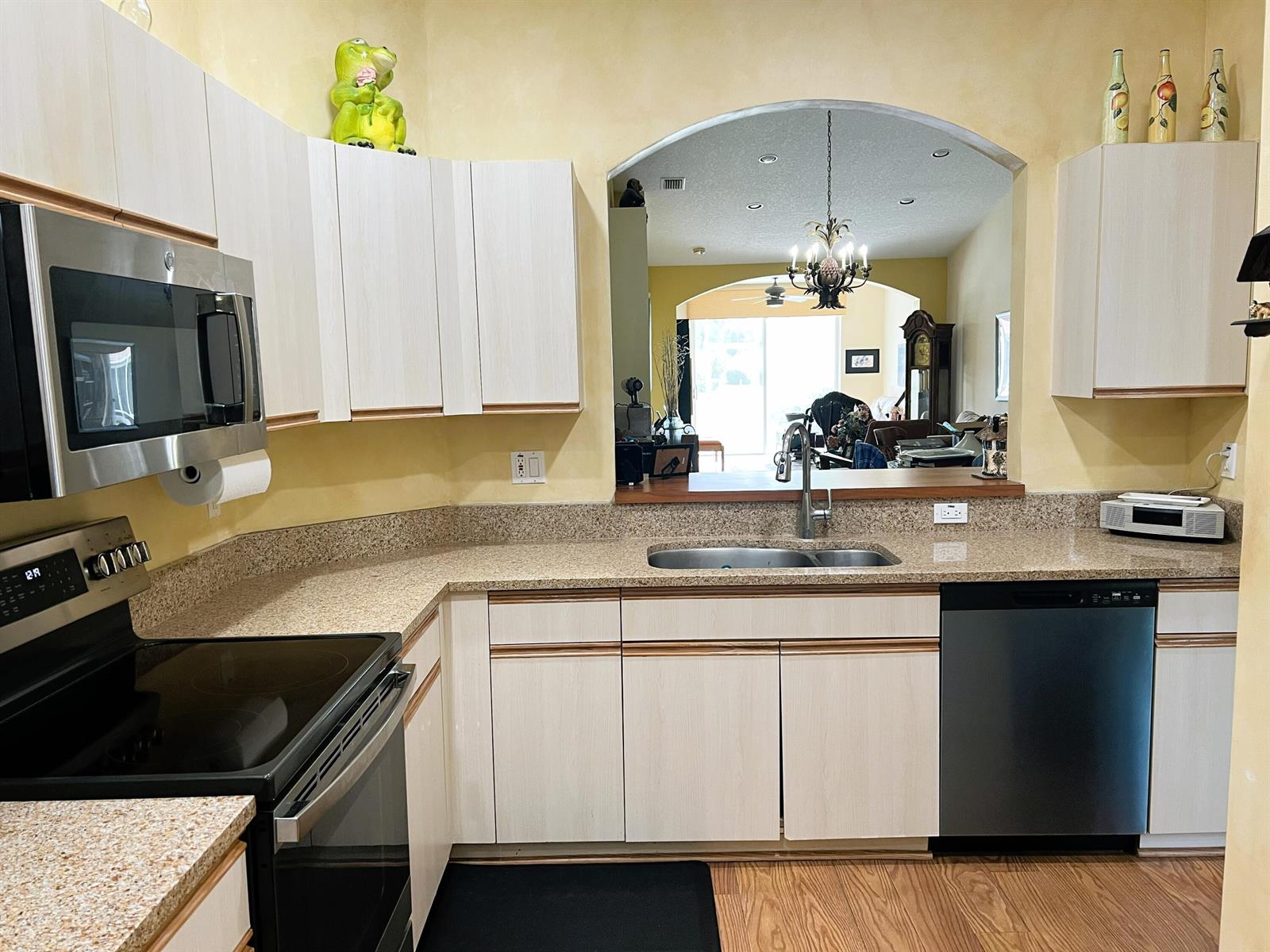 A kitchen features light wood cabinets, granite countertops, stainless steel appliances, and an arched pass-through — 9624 Crescent View Drive N, Boynton Beach FL 33437, BOYNTON BEACH, FL