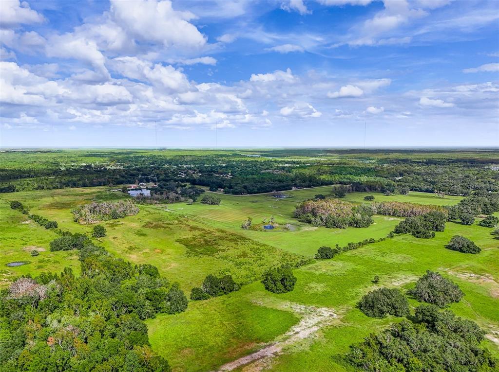 An aerial view shows a large, grassy rural landscape with scattered trees and small ponds — 350 S 5TH STREET, ORLANDO, FL