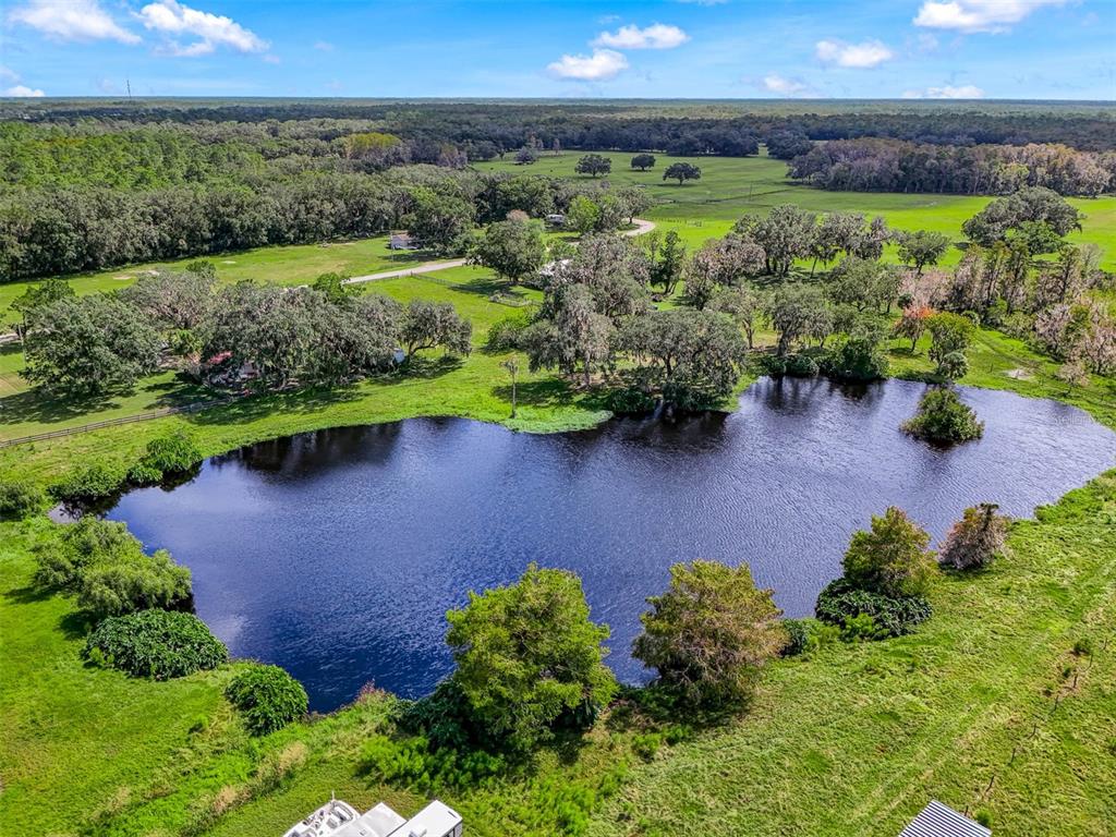 An aerial view shows a large pond surrounded by green pasture and scattered oak trees — 350 S 5TH STREET, ORLANDO, FL