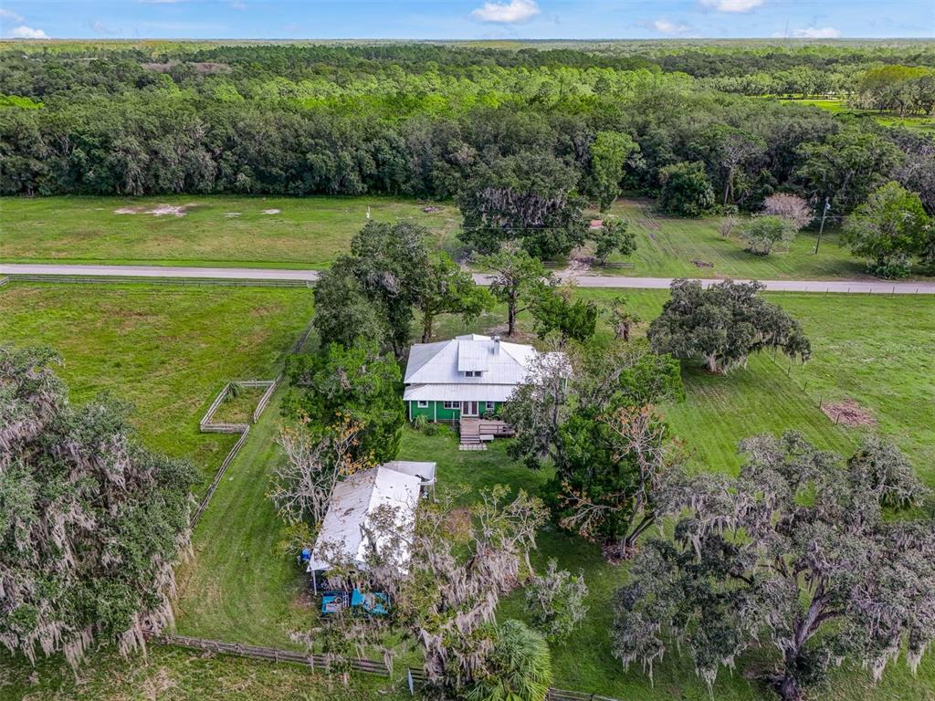 An aerial view shows a house with a white roof surrounded by trees and pastures — 350 S 5TH STREET, ORLANDO, FL