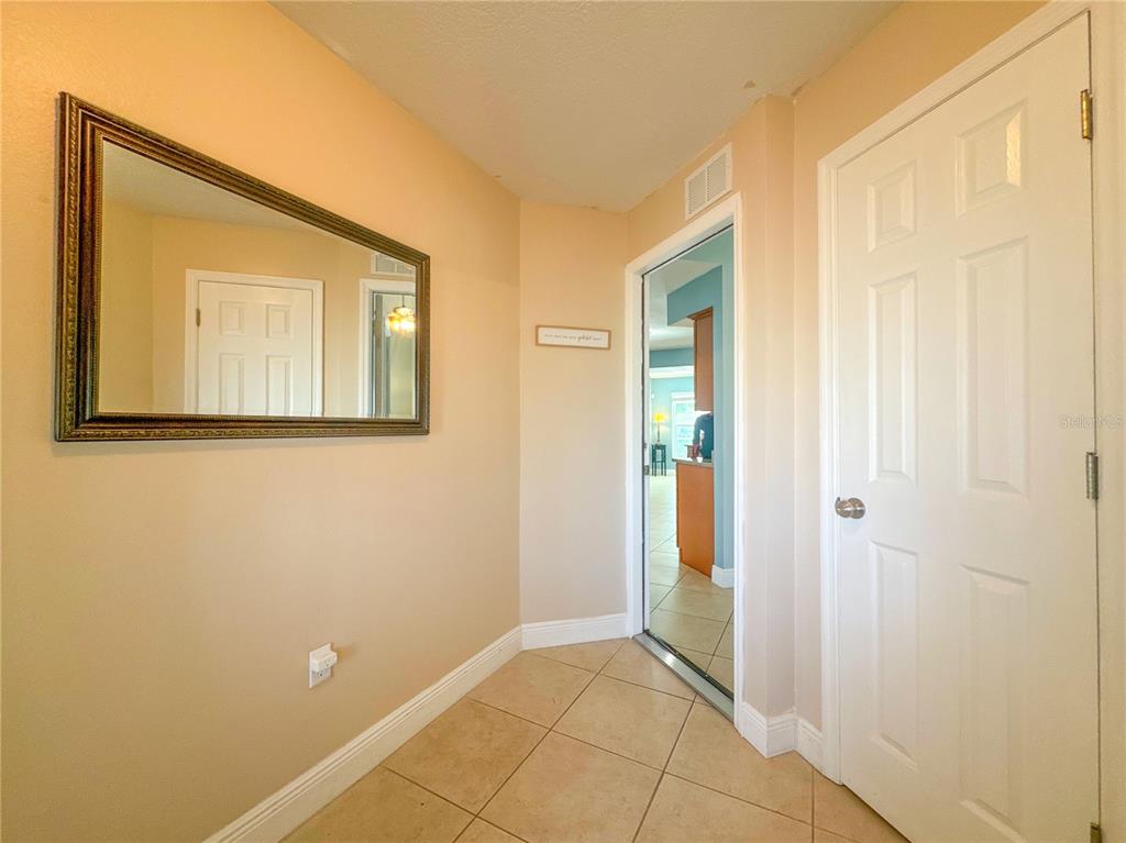 A covered patio features tiled flooring, a ceiling fan, and two sliding glass doors — 707 POWDER HORN ROW, LAKELAND, FL