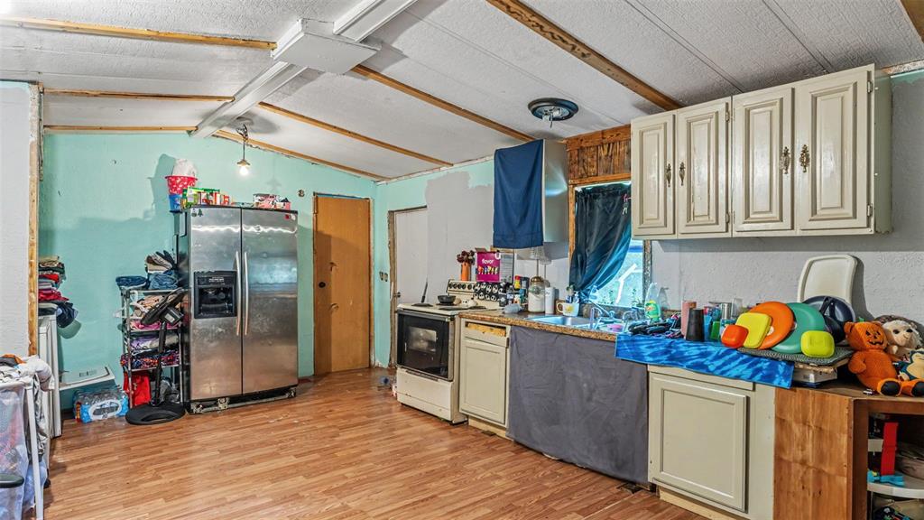 A kitchen features light-colored cabinets, a stainless steel refrigerator, a stove, and wood-look flooring — 2220 ELLIE ROAD UNIT B, AUBURNDALE, FL
