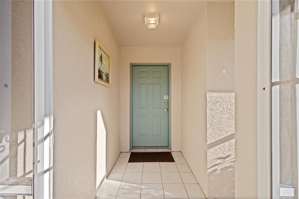 A light blue front door is centered at the end of a tiled entryway — 12454 SW KINGSWAY CIRCLE UNIT 202, LAKE SUZY, FL