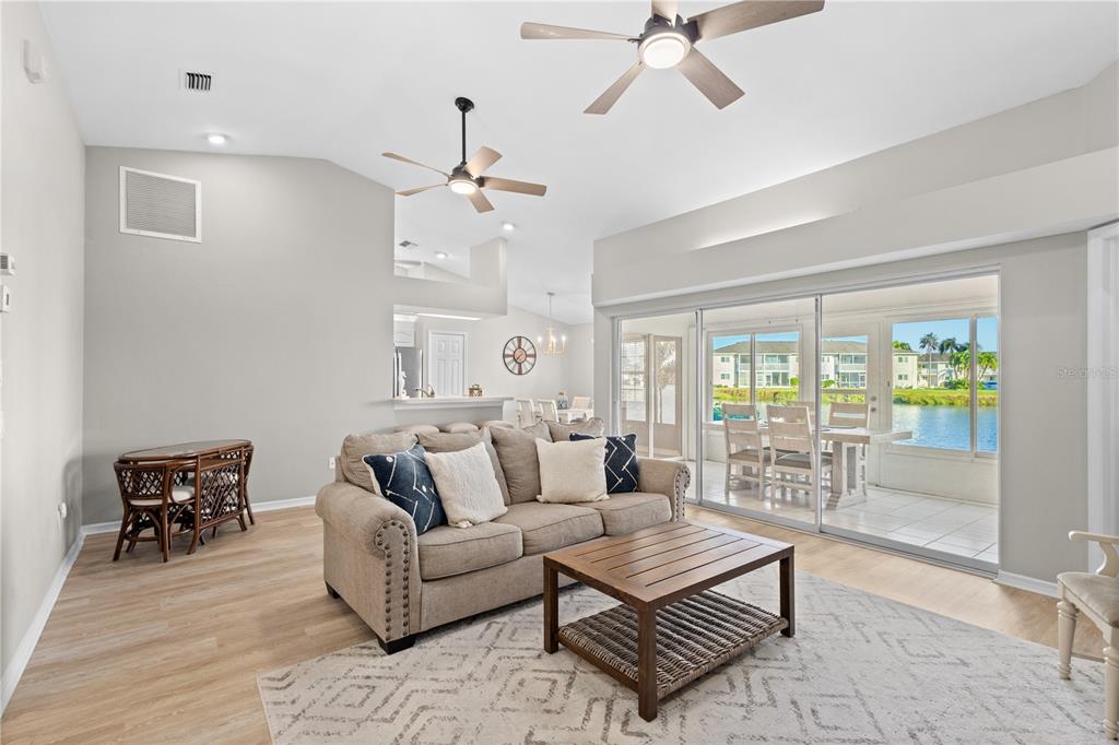 A living room with a beige sofa, wood coffee table, and sliding doors overlooking water — 12454 SW KINGSWAY CIRCLE UNIT 202, LAKE SUZY, FL