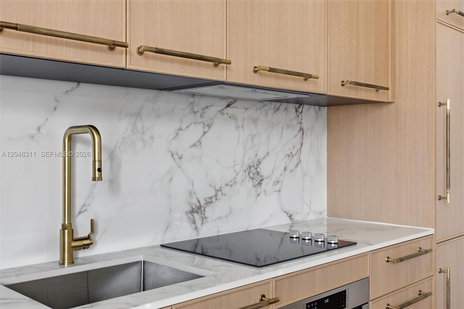 A modern kitchen features light wood cabinets, a marble backsplash, and gold-toned hardware — 2700 NW 2nd Ave # 432, Miami FL 33127, MIAMI, FL