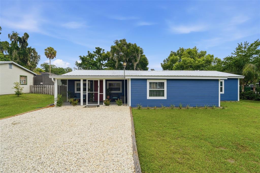 A blue single-story house with a white metal roof and a gravel driveway — 471 PINEGROVE STREET, DELAND, FL