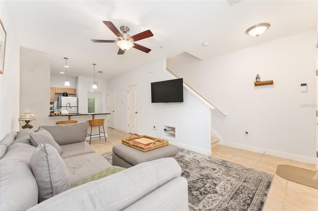 A living room with a gray sectional sofa, a television, and an open kitchen area — 2946 SW 35TH PLACE UNIT 42, GAINESVILLE, FL