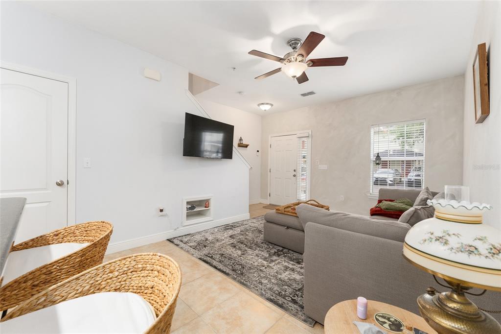 A living room with a gray sofa, a wall-mounted television, and a ceiling fan — 2946 SW 35TH PLACE UNIT 42, GAINESVILLE, FL