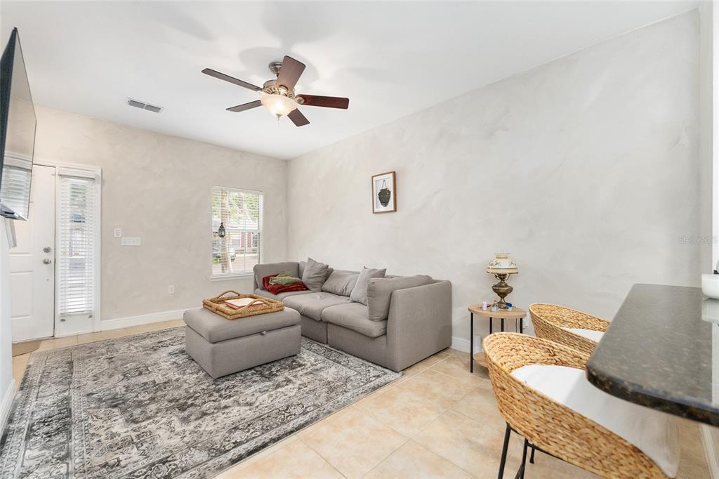 A living room features a gray sectional sofa, an ottoman, and a patterned area rug — 2946 SW 35TH PLACE UNIT 42, GAINESVILLE, FL