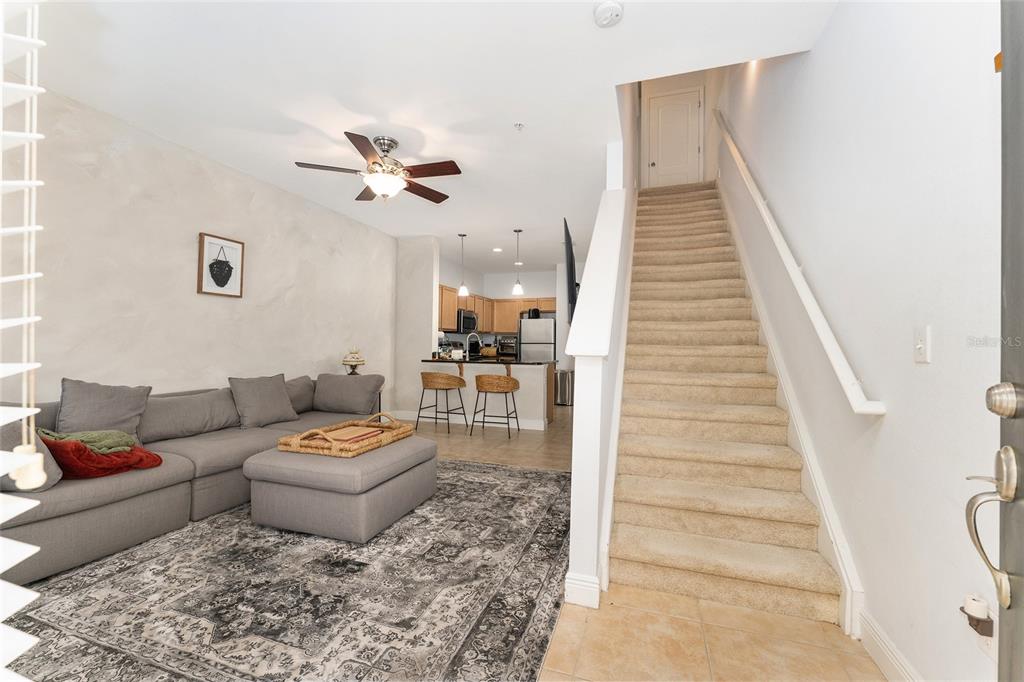 A living room with a gray sectional sofa, patterned rug, and stairs leading upstairs — 2946 SW 35TH PLACE UNIT 42, GAINESVILLE, FL