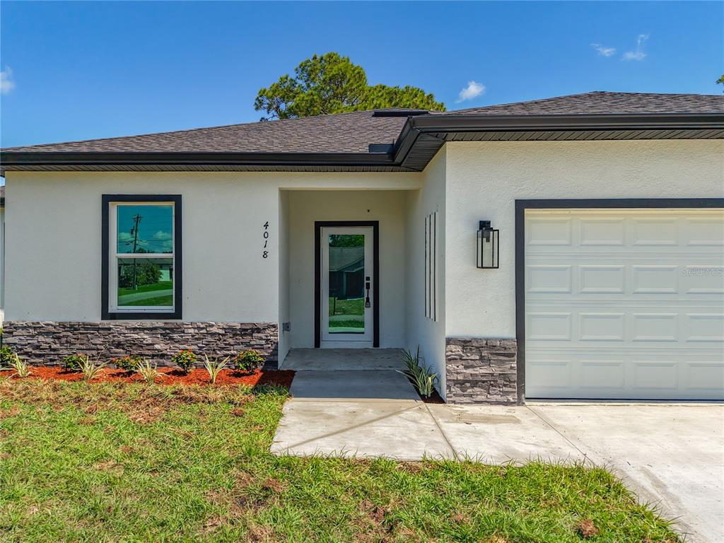 The exterior of a single-story house features a stone-accented facade, a garage, and a walkway — 4018 3RD STREET W, LEHIGH ACRES, FL