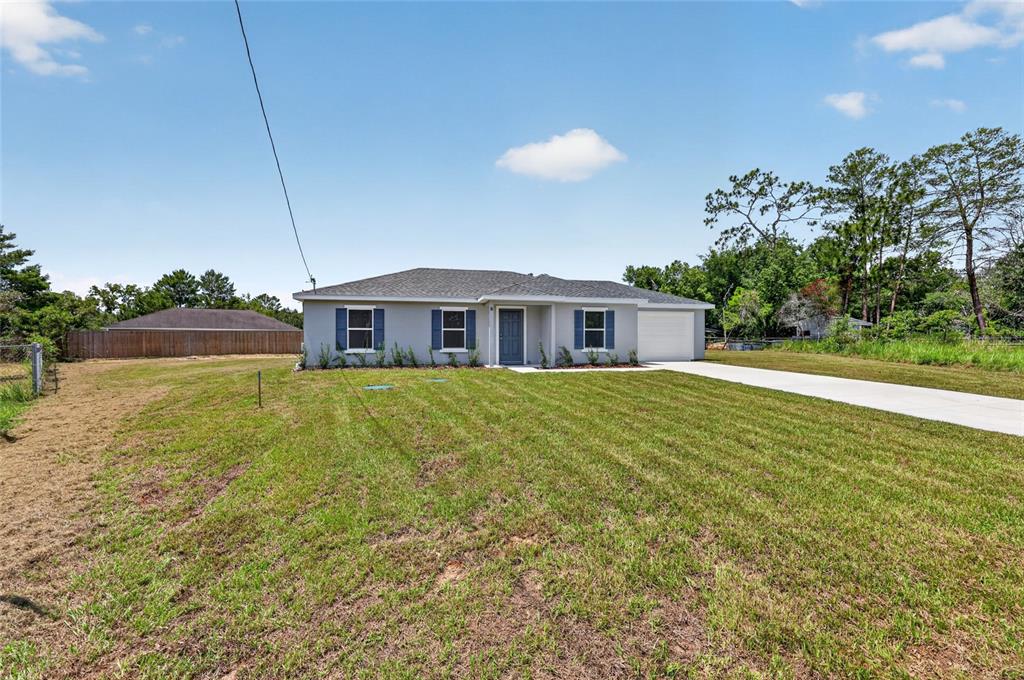 A single-story house with a gray exterior, blue shutters, and a concrete driveway — 8 OAK CIRCLE TRACE, OCALA, FL