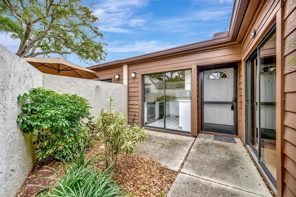 A patio area features a concrete floor, a sliding glass door, and a white entry door — 2925 PARK LAKE DRIVE UNIT 12, BRADENTON, FL
