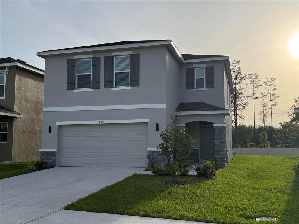A two-story house with a gray stucco exterior, stone accents, and a two-car garage — 10507 TUCKER ROAD, WEEKI WACHEE, FL