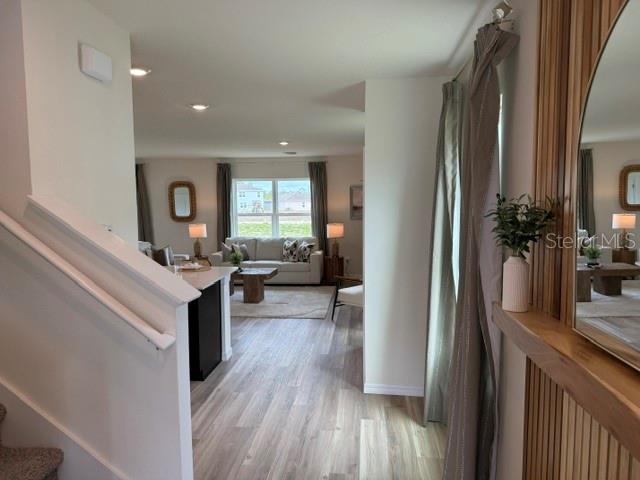 A view from a staircase looking into a living room with light wood-look flooring — 10507 TUCKER ROAD, WEEKI WACHEE, FL