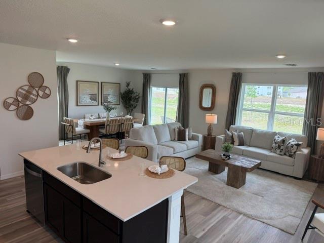 An open-concept living and dining area features a kitchen island, neutral furniture, and wood flooring — 10507 TUCKER ROAD, WEEKI WACHEE, FL