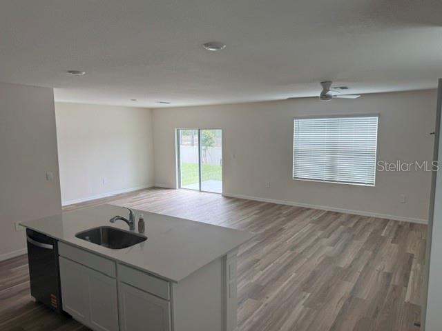 A kitchen island with a sink overlooks an open-concept living area with wood-look flooring — 10507 TUCKER ROAD, WEEKI WACHEE, FL