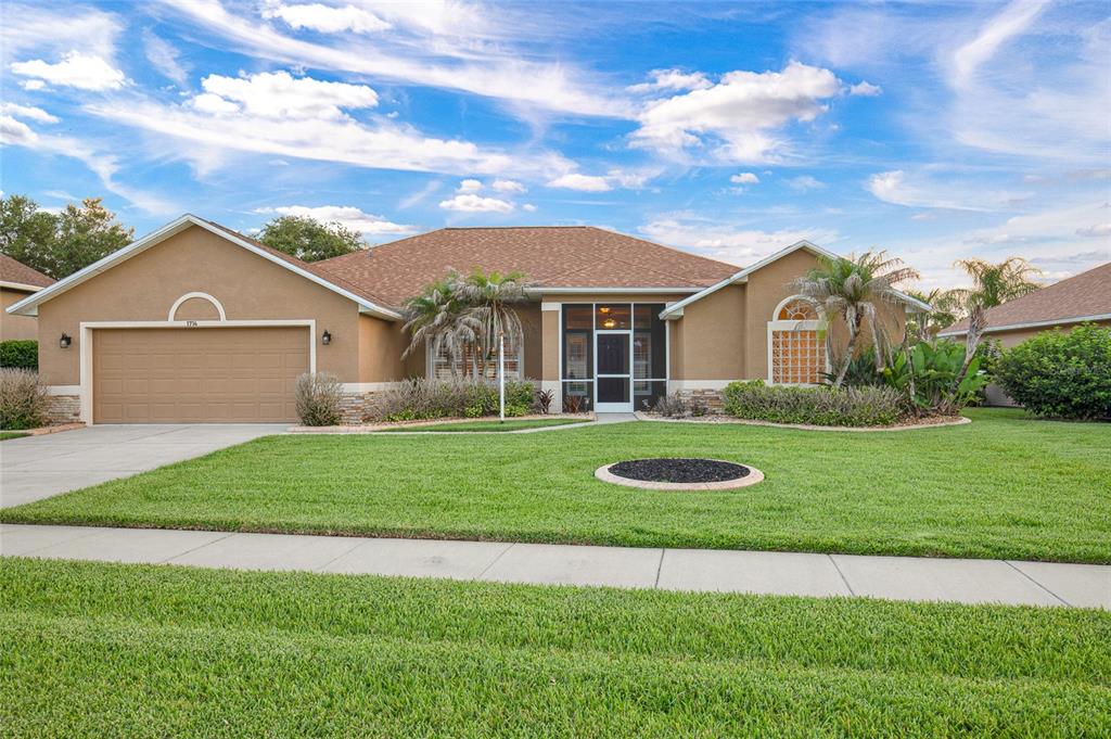 A single-story tan house with a two-car garage, a screened entryway, and a front lawn — 1714 CREEKWATER BOULEVARD, PORT ORANGE, FL