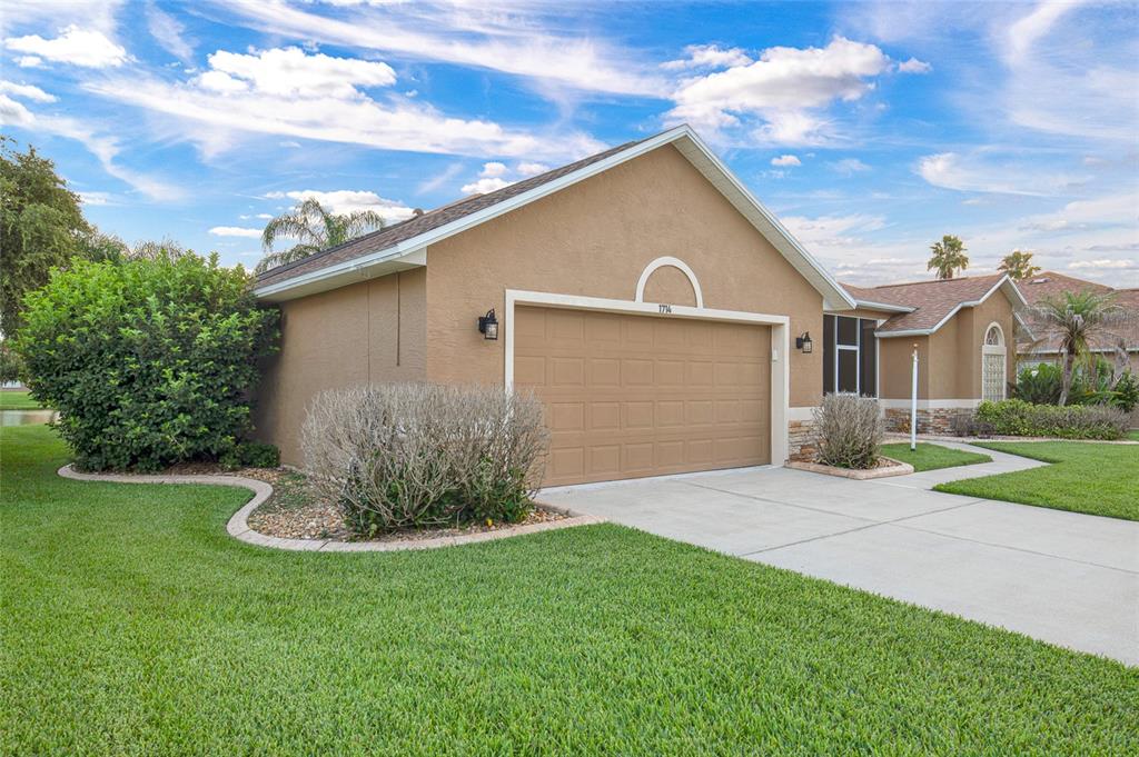 A tan house with a two-car garage and a landscaped front yard under a blue sky — 1714 CREEKWATER BOULEVARD, PORT ORANGE, FL