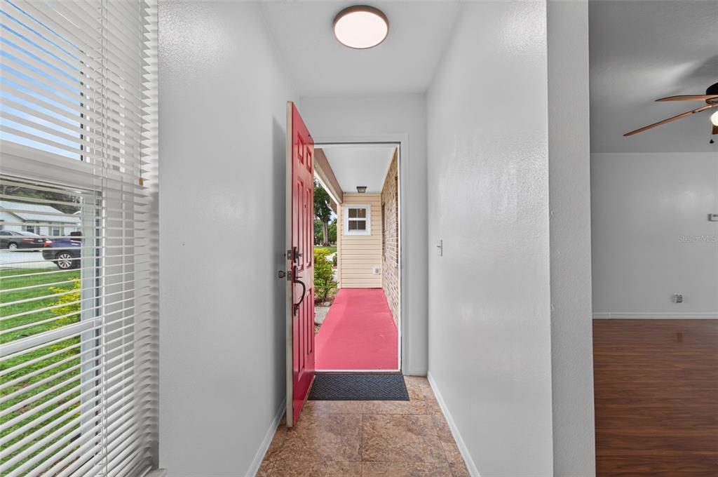 An entryway with tile flooring, a red front door, and a view of the exterior — 3341 NW 44TH COURT, OCALA, FL