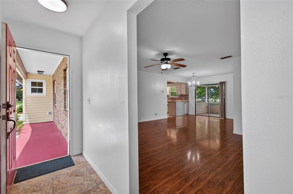 An open doorway reveals a living area with wood-look flooring and a ceiling fan — 3341 NW 44TH COURT, OCALA, FL